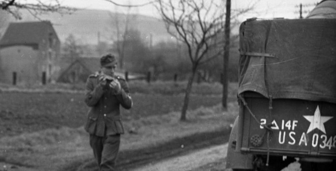 Ankündigungsbild zur Digitalen Ausstellung des Stadtarchivs zum Kriegsende vor 80 Jahren Barrierefreier Text: Neben dem abgesetzten Text „erinnern, gedenken, gestalten …“ in der linken, oberen Ecke des Bildes und der Überschrift „80 Jahre Kriegsende in Lemgo“ zeigt das Archivbild ein US-amerikanisches Militärfahrzeug und einen Soldaten auf einer Landstraße. Im Hintergrund des Bildes ist vermutlich eine Mühle und Hügel zu erkennen.